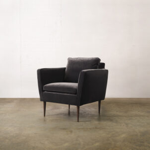 Black velvet armchair with high armrests and dark wooden legs