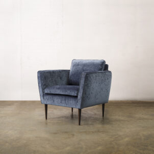 Navy blue chenille armchair with high armrests and dark wooden legs